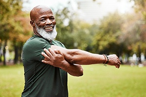 Senior man in field smiling and stretching