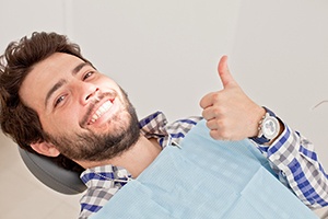 Male patient lying back in chair giving thumbs up
