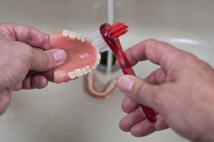 a person cleaning their dentures