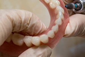 Lab technician filing dentures