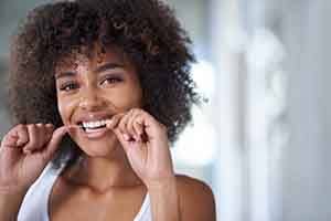 Patient in Springfield flossing around their dental implants