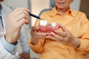 a dentist pointing to a dental implant model